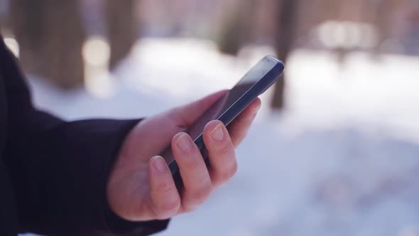 Close Up of Man Hands Using Phone Outside on a Winter Snowy Day