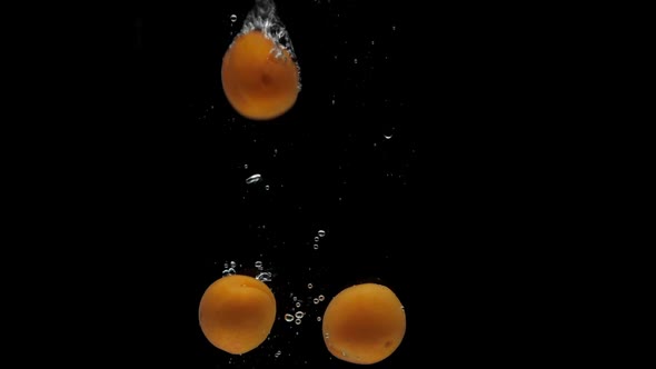 Slow Motion Apricot Falling Into Transparent Water on Black Background