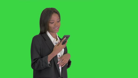 Smiling Black Woman Texting on Her Cell Phone on a Green Screen, Chroma Key.