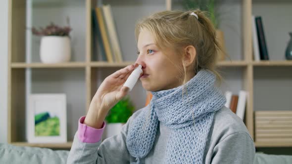 A Woman with Fever and Runny Nose Uses Nasal Spray at Home