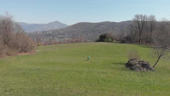 Aerial: man having fun by riding mountain bike in the grass on sunny day, scenic alpine landscape