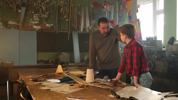 An Experienced Craftsman Teaches a Boy How to Model Aircraft