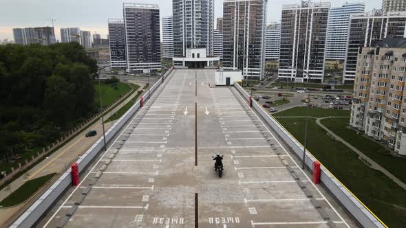 Man Riding Motorbike on Top of the Multilever Parking in City Filmed with Drone