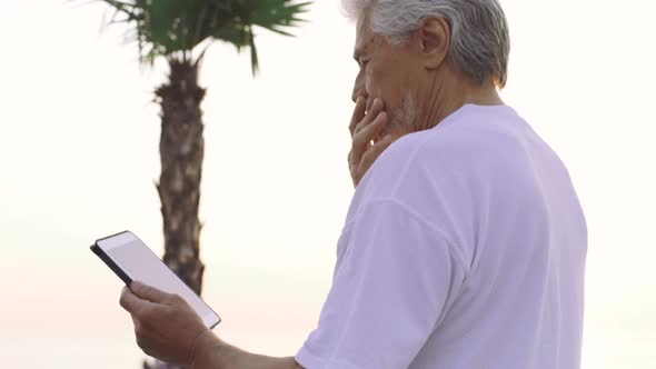 Portrait of Retirement Handsome Senior Man Using Tablet Computer on Seafront