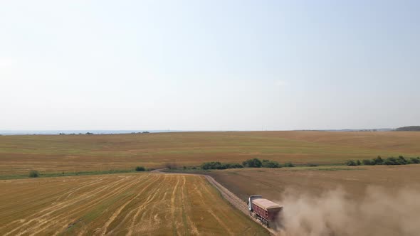 Aerial View of Cargo Truck Driving on Dirt Road Between Agricultural Wheat Fields Making Lot of Dust