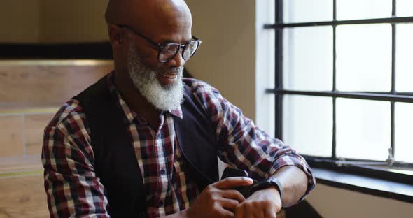 Senior man using his smartwatch on the staircase