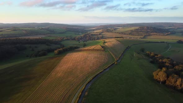 Aerial tilt up shot as the sun sets over the pristine scenery of the South Downs Way, England