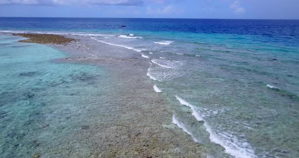 Beautiful above tourism shot of a white sand paradise beach and blue ocean background in vibrant 4K