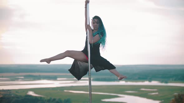 Woman with Blue Braids Dancing on Nature - Shows Tricks and Holding By the Pole