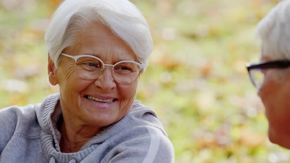 Outdoor Portrait of an Elderly Pensioner Lady Talking with Her Husband in a Park