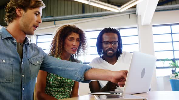 Colleagues discussing with each other over laptop