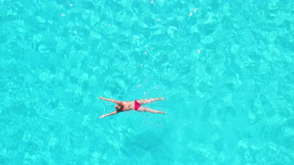 Aerial view of an attractive woman doing breast stroke in crystal clear sea