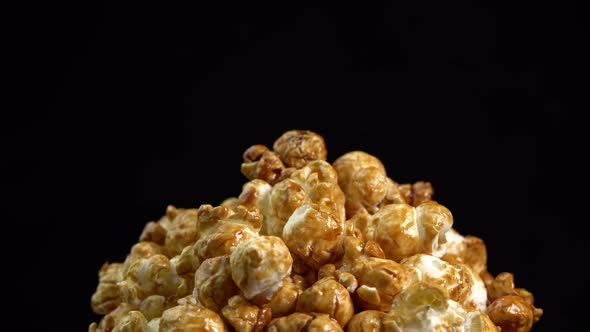 Coffee taste popcorns rotating into the bowl on black background close up. Caramel popcorn. Health