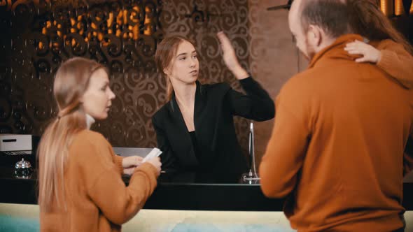 A Family Checking in the Luxury Hotel - a Woman Greeting the Family on the Reception