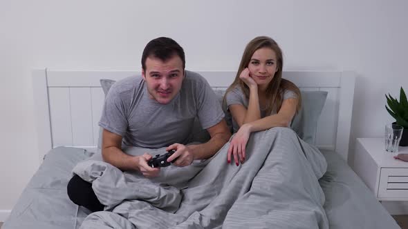 Portrait of Happy Young Couple Posing While Lying in Bedroom on Bed