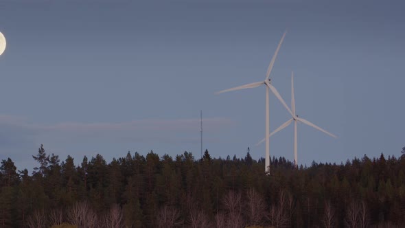 FULL MOON, TWILIGHT, ZOOM OUT - Wind turbines spinning next to a full moon