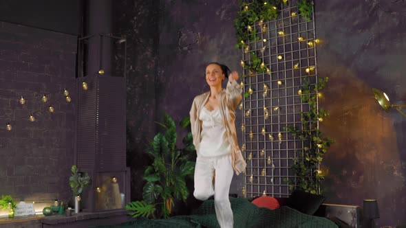 Caucasian Joyful Fresh Brunette Woman in Pajamas Jumping on Bed