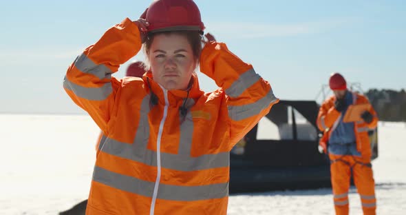 Portrait of Woman Lifesaver Putting on Hardhat Standing on Frozen Lake in Winter