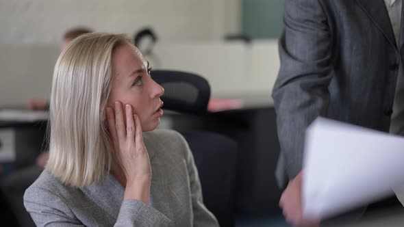 Portrait of Anxious Stressed Caucasian Woman Talking to Unrecognizable Boss Passing Paperwork