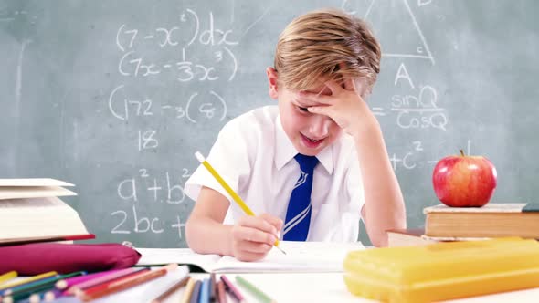 Schoolboy doing his homework in classroom