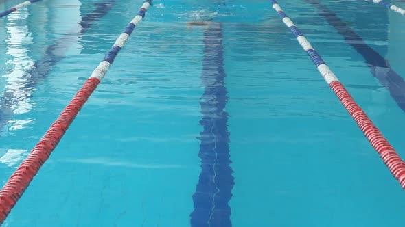 Young Woman in Goggles and Cap Swimming Breaststroke Stroke Style in the Blue Water Indoor Race Pool