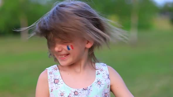 Child Cheerful Girl Happily Shakes Head with Her Cheeks Painted in the Flag of France Her Hair