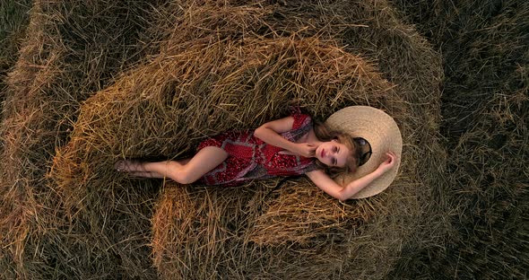 Girl Lying On A Pile Of Hay In A Field At Sunset