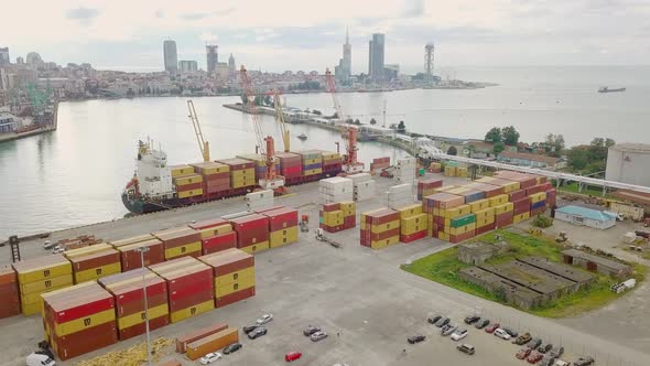 Ship view from a drone. Unloading of containers by a crew and a crane in port