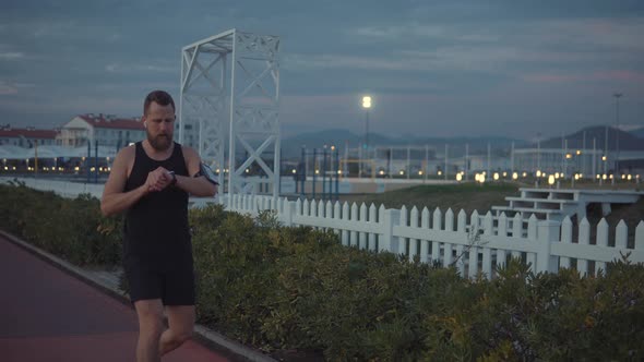 Male Runner Is Training Alone in Evening Time in Darkness in City Park