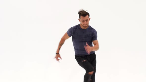 Man Is Dancing Breakdance on the White Background in Simple Grey T-shirt and Grey Jeans. Slow Motion