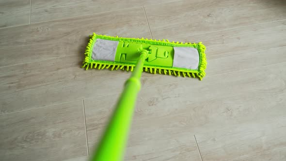 New green mop moving on parquet floor