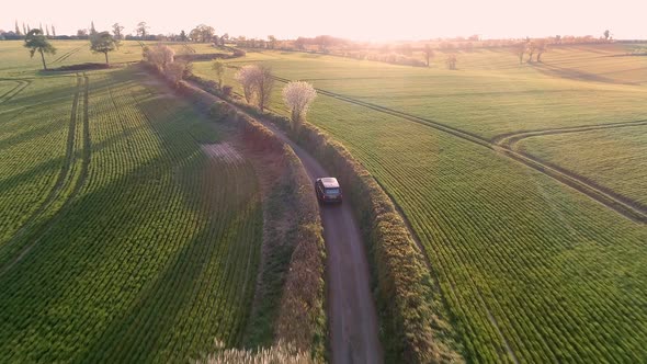 Aerial View of a Luxury SUV Driving Through a Country Lane in the Evening