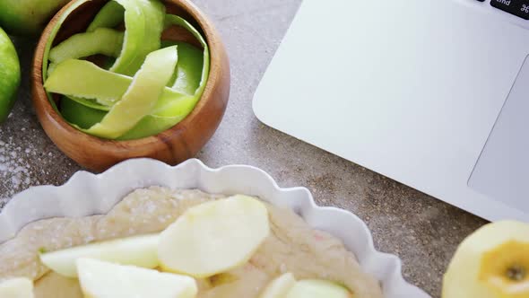 Laptop with apple tart and peeled green apple