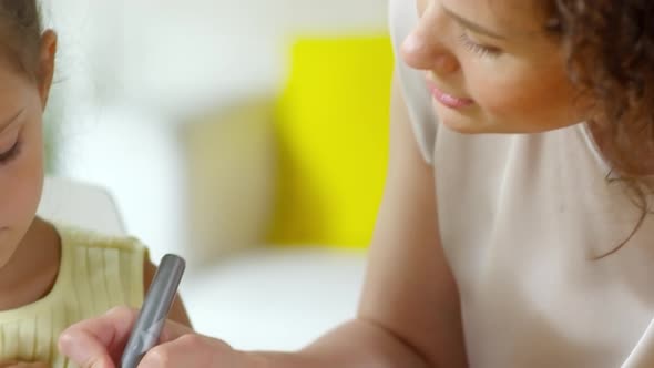 Woman Teaching Little Girl Drawing on Paper