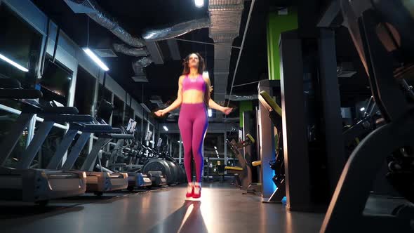 Young woman exercising using skipping rope in gym. Athletic woman training hard at the gym.