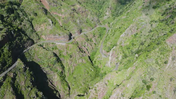 Scenic mountainous road curving along dramatic valley, Madeira; aerial