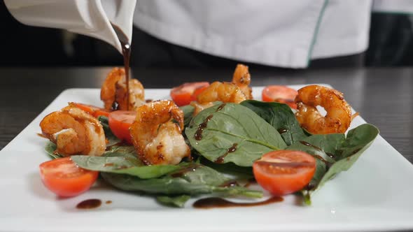 Mediterranean Cuisine. Chef Pours Sauce Over Vegetarian Seafood Salad with Shrimps. Finishing Salad