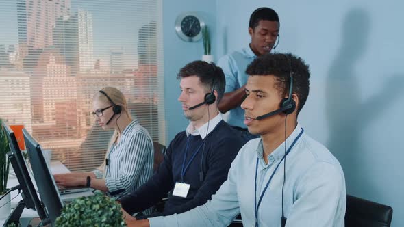 Black Manager Operator Helping His Colleague in Call Center