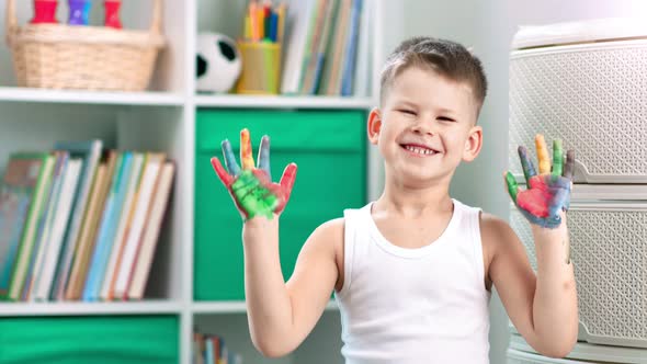 A Happy Little Boy is Painting with His Fingers