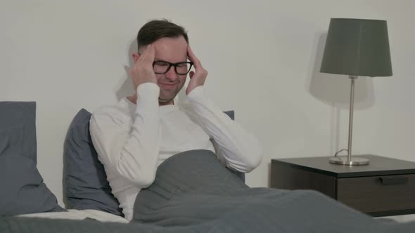 Casual Man Having Headache While Sitting in Bed