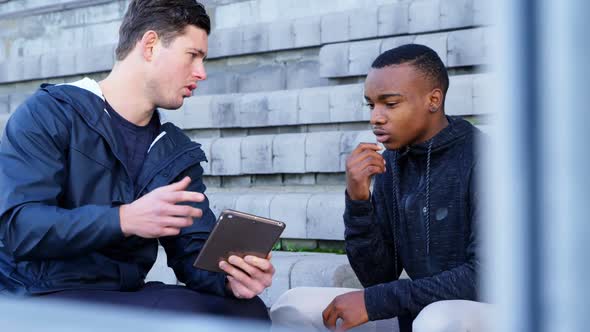 Two disabled athletics discussing over digital tablet 4k