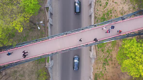 Flying Over the Pedestrian Bridge in the Park on Which People Walk. Spring Outside