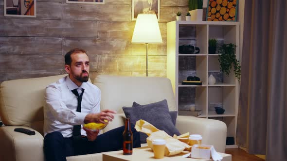Businessman Sitting on Couch Eating Chips