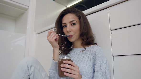 Happy Jolly Lady in Trendy Clothes Tasting Delicious Chocolate Cream Using Spoon