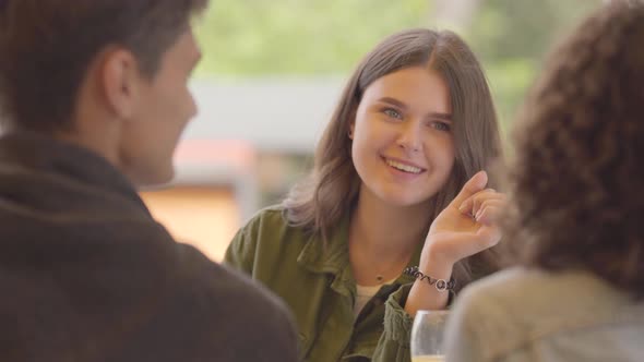 Portrait of Pretty Girl Sitting in a Restaurant in the Company of Friends