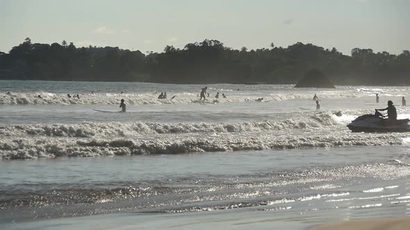 Group of Unrecognizable Surfers Paddling Over Ocean Wave on the Surfboards. Many Tourists Learns To