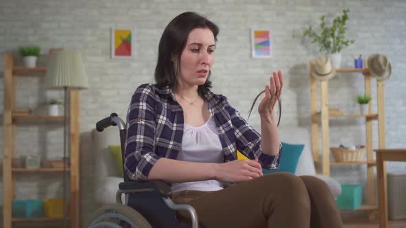 Young Upset Woman in a Wheelchair a Lot of Hair Falls Out After Chemotherapy