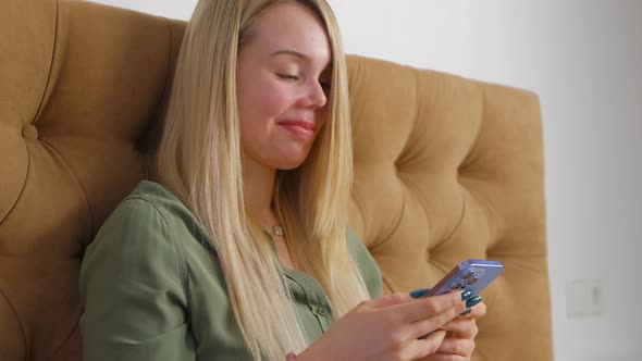 Young woman using modern mobile phone with triple camera for communication online