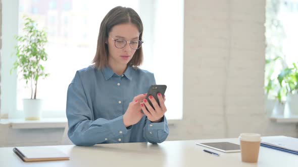 Attractive Young Woman using Smartphone in Office