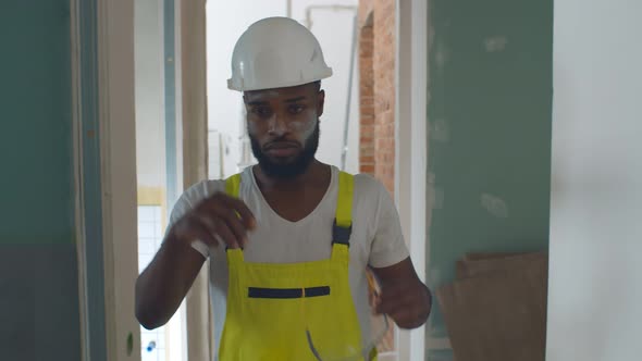 Portrait of Exhausted Afro-american Builder Removing Safety Equipment Finishing House Renovation